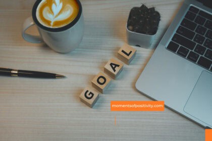 Motivational workspace featuring coffee, laptop, and "GOAL" blocks for positivity and productivity. setting goals